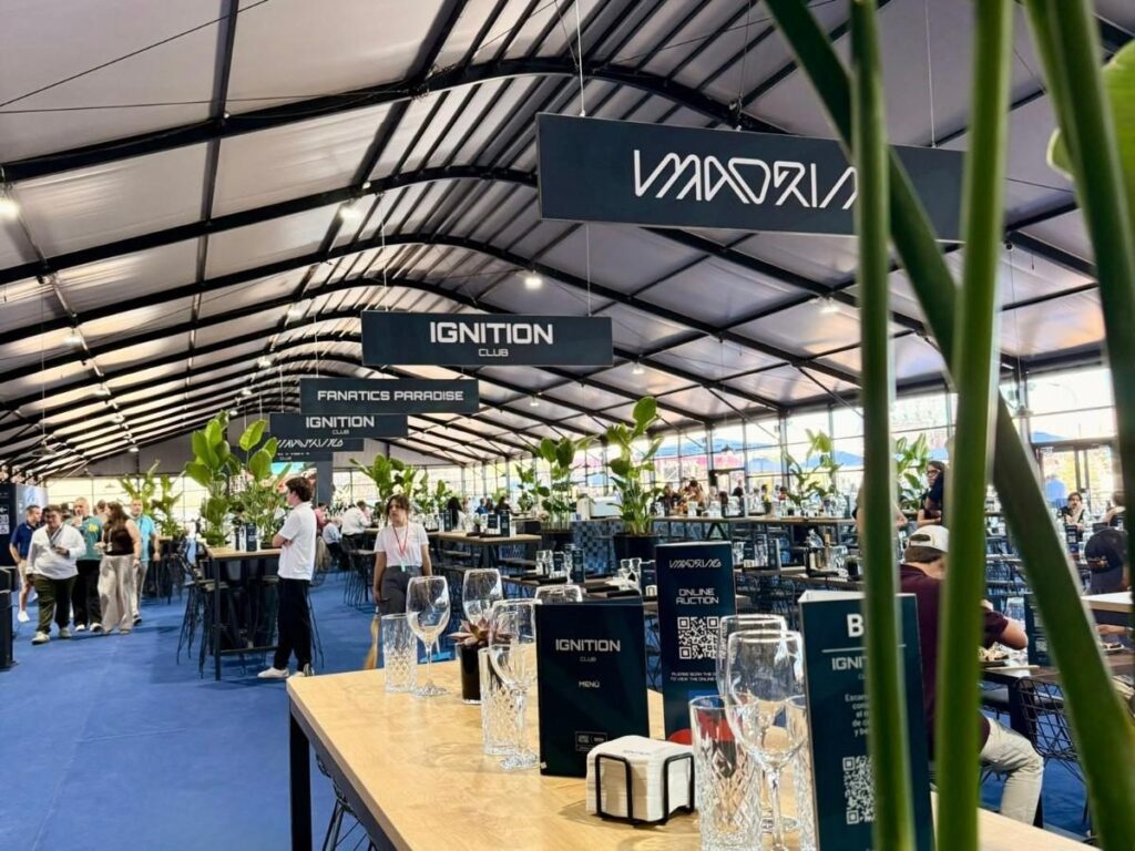 Inside the Ignition Club hospitality tent at MADRING, featuring wooden high tables, crystal glasses, and menus, with the Artigot Catering team serving the guests
