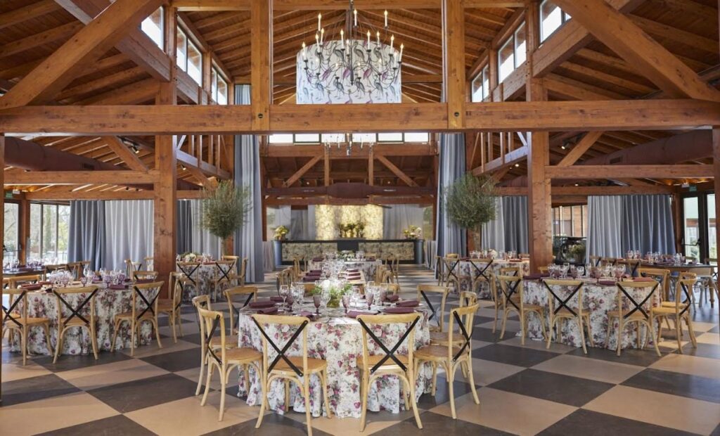 Salón de la finca Initium montado con mesas redondas para el banquete de una boda, en Madrid
